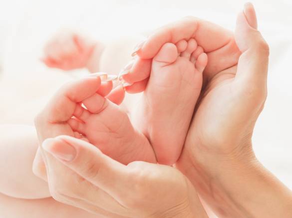 Une maman entoure les mains de son bébé après son accouchement